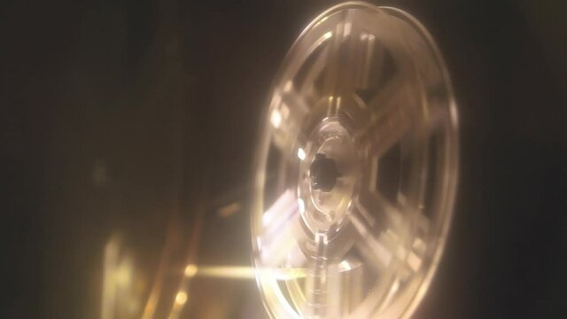 Strong glow: the running reels of a vintage Super 8mm film projector, immersed into the mystic light beam coming out from the front lens.
