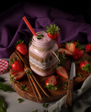 Batido de fresa en vaso de crital r&uacute;stico sobre superficie de madera. Comida saludable.