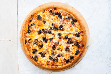 Pizza with mozzarella cheese, ham, mushrooms, chicken and sauce on gray background