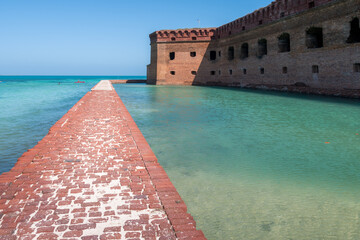 Tall brick walls of an old military fort on an island of Dry Tortugas. Florida. Blue sky, green...