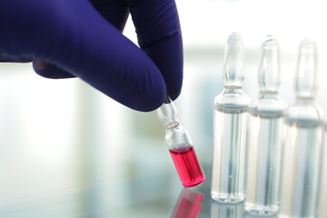 Doctor in rubber blue gloves picks up a bottle of vaccine with his fingers