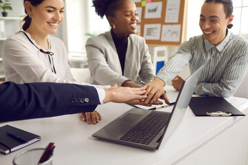 Group of diverse colleagues fold their hands on each other as a symbol of cooperation and support. Business team is set up for a positive result by creating a new business project. Concept of unity.