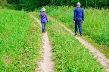 young girl with dad walk along the forest along the road