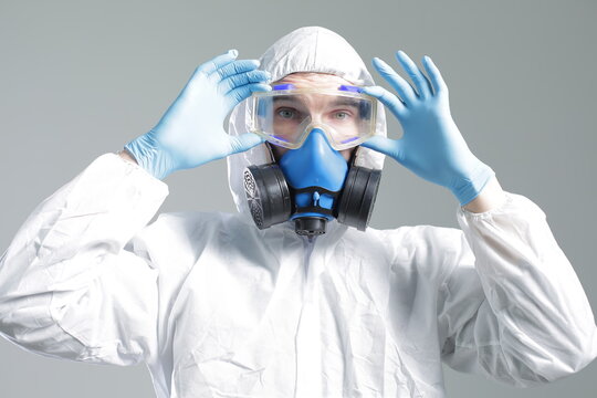 Man in protective suit, goggles, blue rubber gloves and respirator