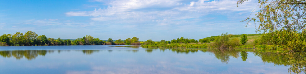 Wide panorama with river and trees reflected in the water