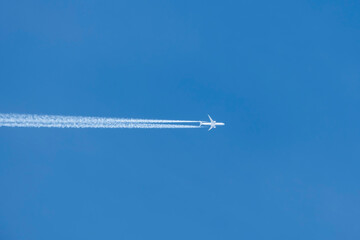 Stunning view of a commercial airplane forming contrails on a blue sky. 