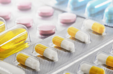 A bunch of medical pills in yellow and other colors. Tablets in plastic packaging.
