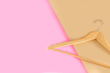 Empty wooden clothes hangers on pastel pink and beige background with copy space. Sale and shopping concept.
