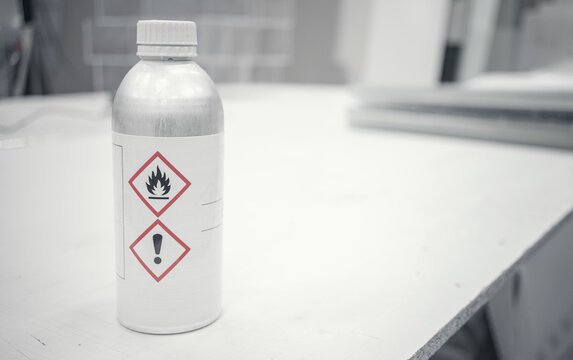 A bottle of toxic liquid for industrial use. Metal bottle of silver color, with warning labels on the instructions