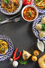 A set of oriental dishes in plates with traditional Uzbek ornament. Pilaf, manti, lagman soup, vegetable salads, tandoor flatbread, samsa, vegetables and spices. Template Uzbek cuisine.