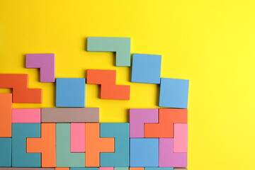 wooden puzzle game in the form of puzzles of different colors on a yellow background close-up selective focus.