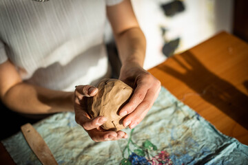 Pottery. A girl with a string in her hands cuts the top layer off clod clay. The process of modeling ceramic ware.