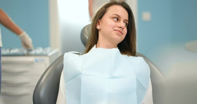 Girl waiting for the dental treatment with dentists preparing on the backgorund