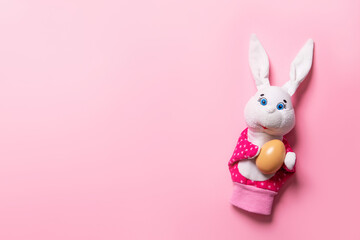 Banner with bunny and an Easter egg on pink background with copy space, empty text place. Christian holiday card. Springtime. Toy theater. Online course for painting eggs. Hand puppet. Childhood play