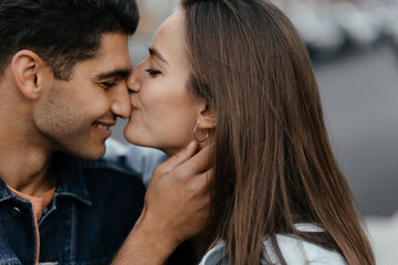 Young beautiful girl kissing his boyfriend's nose. Couple in love in the city. Urban lovestory