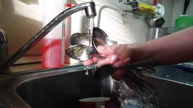 housewife washes spoons and forks
