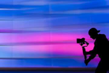 Silhouette of videographer is filming with cinema gimbal video dslr, professional video, videographer in events. Cinema lens on gimbal. Medium shot. Film or cameraman school. Space for text
