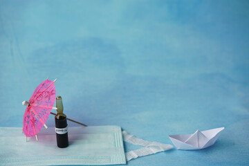 covid-19 concept with blue background, mask and paper ship