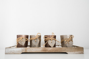 Candles with wooden hearts on wooden stand. Home decor. Hygge concept. White background.