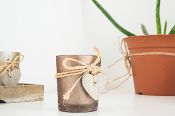 Close-up of candle with wooden heart. Green plant. Home decor. Hygge concept. White background.
