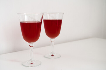 Close-up of couple of glasses with wine on table. White background.