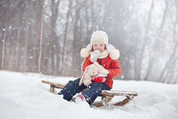 Fototapeta na wymiar a little girl in a fluffy hat walks on a snowy winter day
