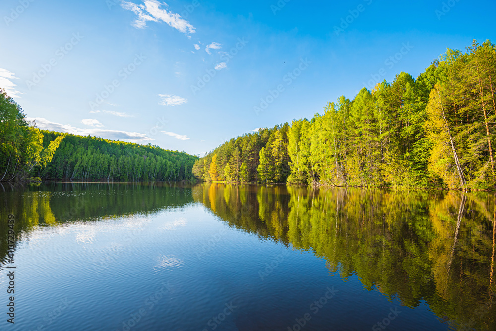 Wall mural panoramic landscape on a sunny day on the river with the sky in the clouds and the reflection in the