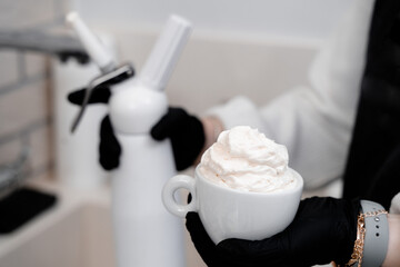 Cream on a cup of coffee in the hands of the barista. Coffee with cream.