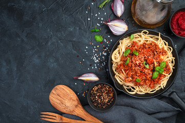 Classic Italian dish pasta bolognese with basil on a dark background. Cooking concept. Top view and copy space.