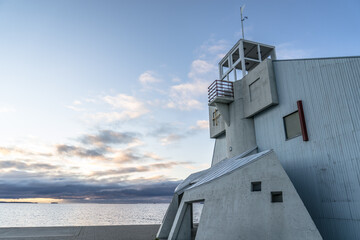 side view of Nallikari lighthouse in Oulu, Finland at Baltic sea. Modern tower at the end of stone paved pier with beautiful evening cloudy skyline