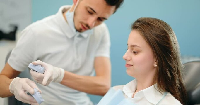 Dentist showing a jaw model, explaining to the young patient the process of orthodontic treatment. Girl with dental braces with a dentist