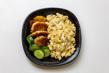 fried fish cakes with pasta and cucumber on a plate