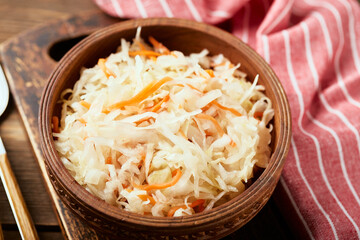 Sauerkraut, fermented cabbage with carrots in bowl on wooden background. Superfoods for support the immune system. 