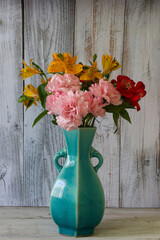 青い花瓶に活けたカーネーションとアルストロメリアの花束