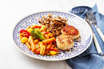 Plate with fried vegetables, carrots, broccoli, baby corn, bell peppers, roasted champignons and two chicken balls