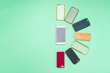 Choice of multicolored plastic back covers for mobile phones on green background with a smart phone on the side