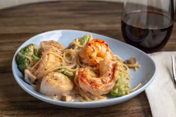 Shrimp and scallop linguine with broccoli, mushrooms and a glass of red wine