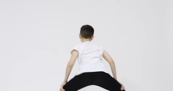 Back view of cute teenager intensely moving shoulders and upper body, shaking buttocks and thrusting hips while twerking. Isolated on white background