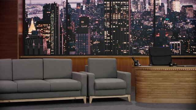 ZOOM IN view of an empty talk show studio, chair, sofa and host table. TV broadcast style show. Shot with RED cinema camera