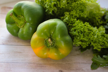 The concept of healthy eating. Green dill leaves and arugula, and lettuce along with green bell pepper on a wooden background