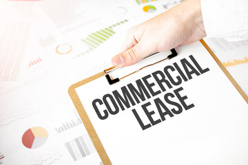 Text commercial lease on white paper plate in businessman hands with financial diagram. Business concept
