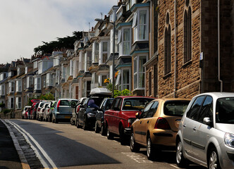 Naklejka premium Cars Parking In Front Of Charming Row Houses At Bedford Road St Ives Cornwall England On A Sunny Summer Day With A Few Clouds In The Sky