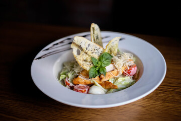 Classic Caesar salad with grilled chicken breast and half of egg in white ceramic plate. Served old dark blue wooden background.