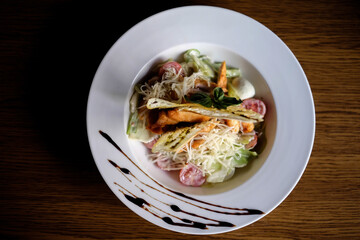 Classic Caesar salad with grilled chicken breast and half of egg in white ceramic plate. Served old dark blue wooden background.