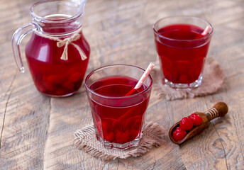 Two glasses of homemade cherry juice on wooden background. Selective focus.