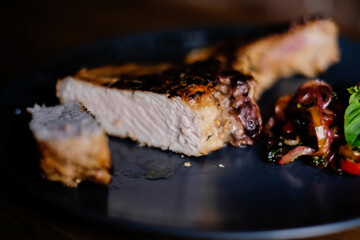 grilled steak on the bone on a blue plate on a wooden table