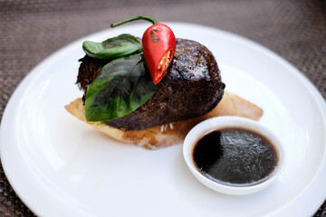 grilled beef fillet medallions on noodles with red hot chili pepper and salad leaf on white plate
