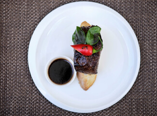 grilled beef fillet medallions on noodles with red hot chili pepper and salad leaf on white plate
