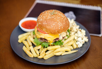 Fast food and unhealthy eating concept, french fries, ketchup and burger on the black plate