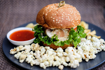 Fast food and unhealthy eating concept, french fries, ketchup and burger on the black plate